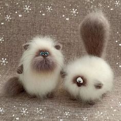 two stuffed animals sitting next to each other on a cloth covered surface with snowflakes