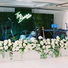 the stage is decorated with white flowers and greenery