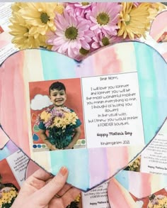 someone is holding up a heart shaped card with flowers in the middle and an image of a child on it