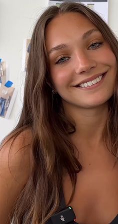 a woman with long brown hair smiling at the camera