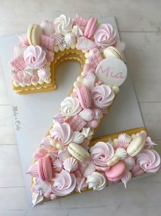 the number two cake is decorated with pink and white icing, flowers, and seashells