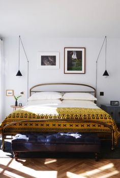 a bed sitting in a bedroom next to a window with pictures on the wall above it