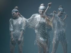 three women in silver dresses standing under water