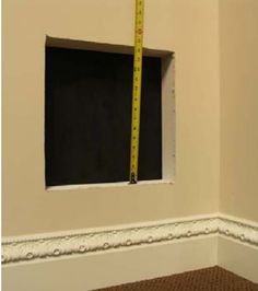 an empty room with a measuring tape on the wall and a window in the corner