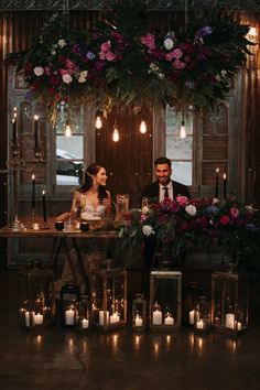 a man and woman sitting at a table with candles