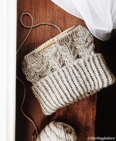 two balls of yarn sitting on top of a wooden table next to a ball of string