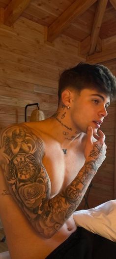 a man with tattoos sitting on a bed