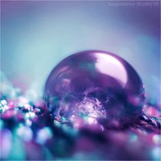 a crystal ball sitting on top of a pile of purple and blue beads in front of a green background