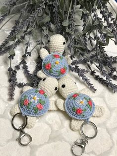 three crocheted teddy bears with flowers on them are sitting next to a potted plant