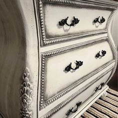 an old white dresser with black handles and knobs