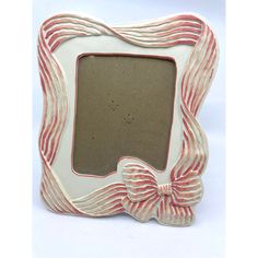 a white and red photo frame with a bow on the front, sitting against a white background