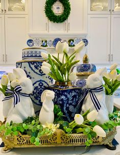 an arrangement of white tulips and other flowers in blue and white vases