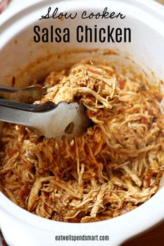 slow cooker salsa chicken in a white crock pot with a spoon scooping out