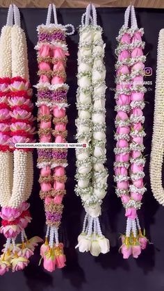 several different types of flower garlands hanging on a black surface with white and pink flowers