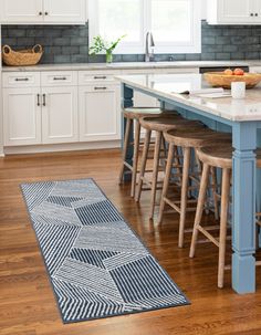 a blue kitchen island with stools next to it and an area rug on the floor