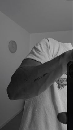 a man with a tattoo on his arm is taking a selfie in the mirror