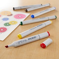 several markers are laying on the table next to some paper