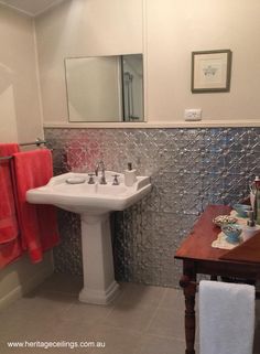 a white sink sitting under a bathroom mirror next to a wooden table with two towels on it