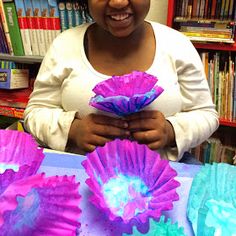 a woman is holding some paper flowers in her hands