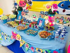 a blue table topped with lots of desserts and candy bar items next to a shark banner