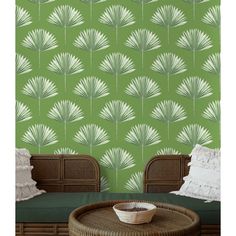 a green wallpaper with palm leaves on it and a wicker table in front