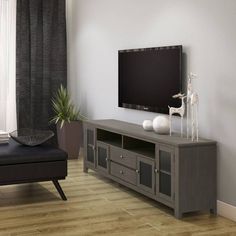 a flat screen tv sitting on top of a wooden entertainment center next to a window