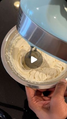 a person is using a mixer to whip cream into a bowl with the lid down