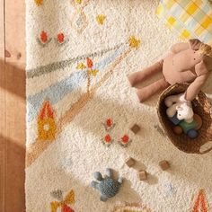 a teddy bear laying on top of a rug next to a stuffed animal in a basket