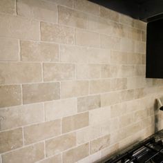 a stove top oven sitting inside of a kitchen next to a wall with a brick pattern on it