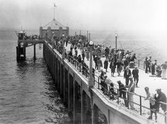 many people are standing on the pier by the water