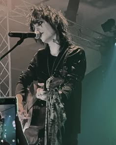 a woman standing in front of a microphone on top of a stage