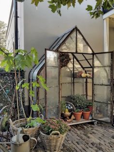 an old greenhouse with potted plants in it and other pots on the ground next to it