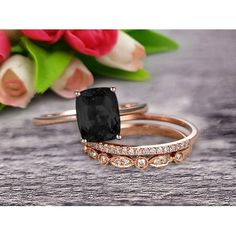 an image of two wedding rings with black stone and diamonds on the sides, one in rose gold