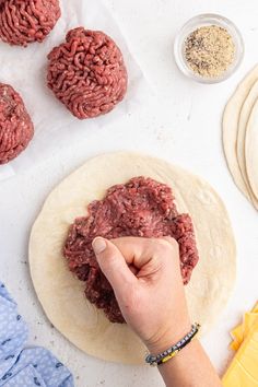 a person making hamburger patties on top of floured tortilla paper and other ingredients