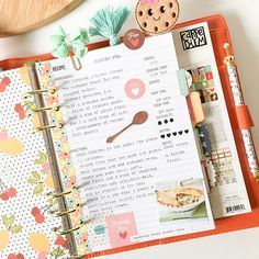 an open planner book on top of a desk next to a cookie and other items