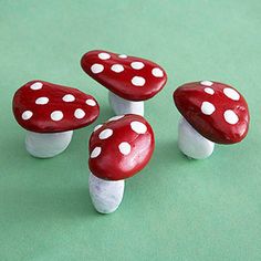 three red and white mushrooms sitting on top of a green surface