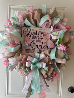 a wreath that says bunny kisses and easter wishes hanging on the front door with ribbons attached to it