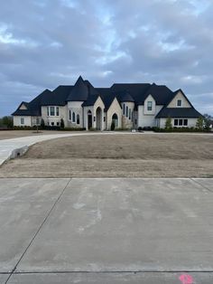 a large house with lots of windows in the middle of an empty lot on a cloudy day