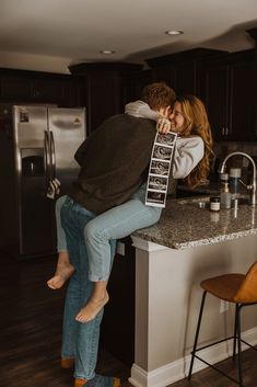 a man and woman sitting on top of a kitchen counter