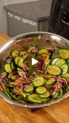 a metal pan filled with cucumbers and onions on top of a wooden table