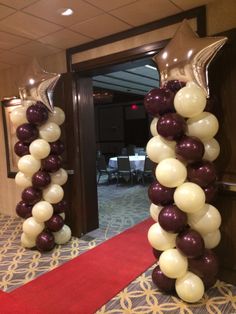 balloons are arranged in the shape of an arch on a red carpeted area with chairs and tables