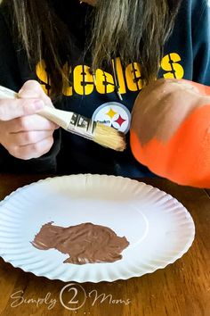 a person with long hair painting a paper plate