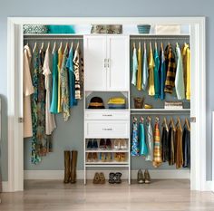 an open closet with clothes and shoes hanging on the shelves, in front of a blue wall