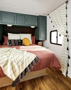 a bed in a room with wooden floors and green cabinets on either side of the bed