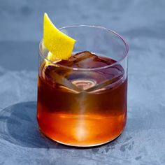 a close up of a drink in a glass with a lemon wedge on the rim