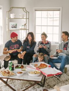 a group of people sitting around a table eating pizza