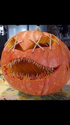 a carved pumpkin with sharp teeth and fangs on it's face, sitting on a table