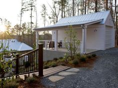 a small white house in the woods with a deck and picnic table next to it