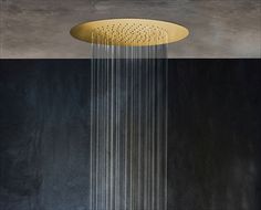 a shower head with water running down it's side and black walls in the background