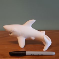 a white dolphin figurine next to a black marker